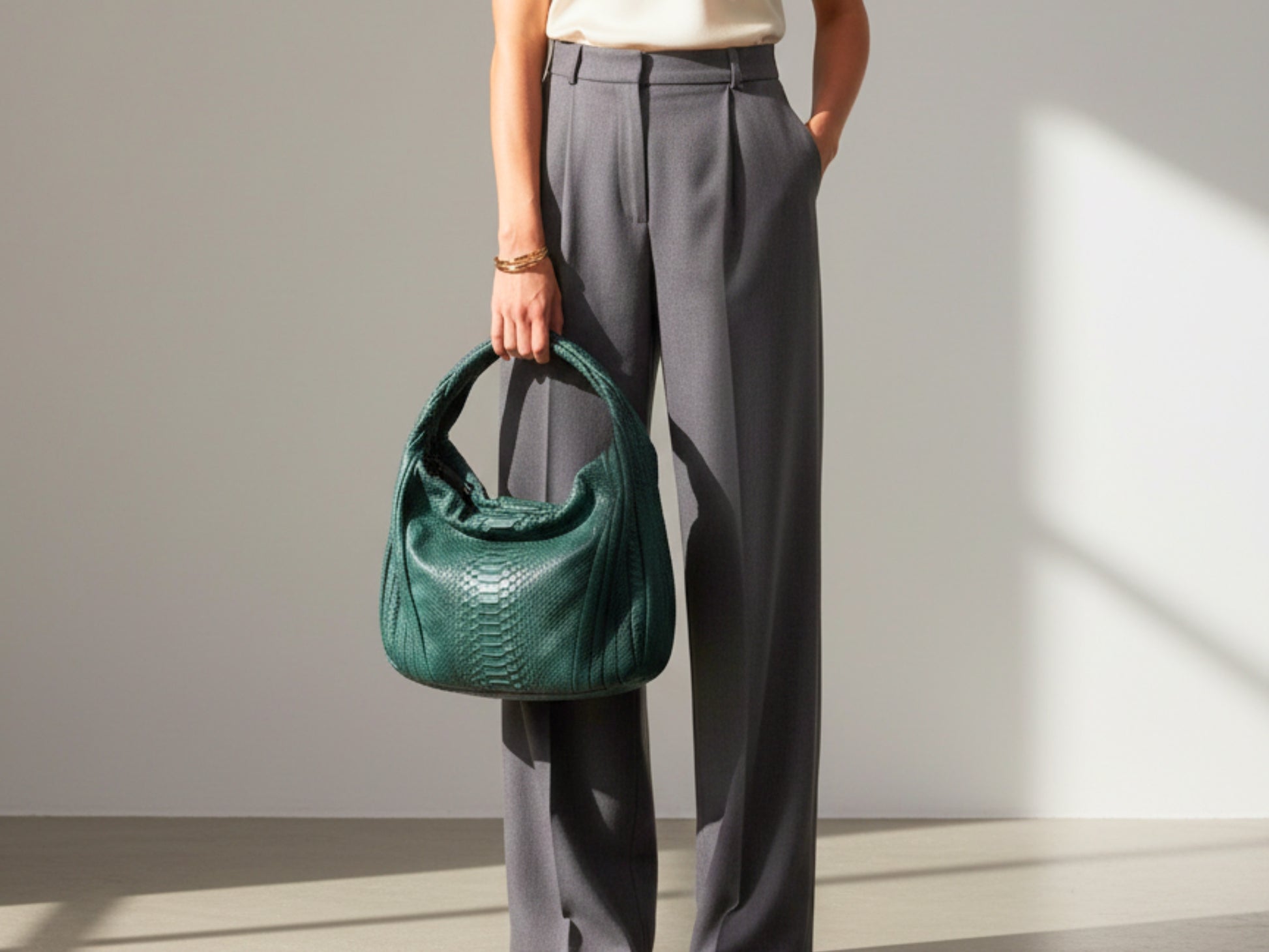 Person holding a green handbag against a neutral background