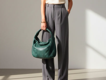 Person holding a green handbag against a neutral background