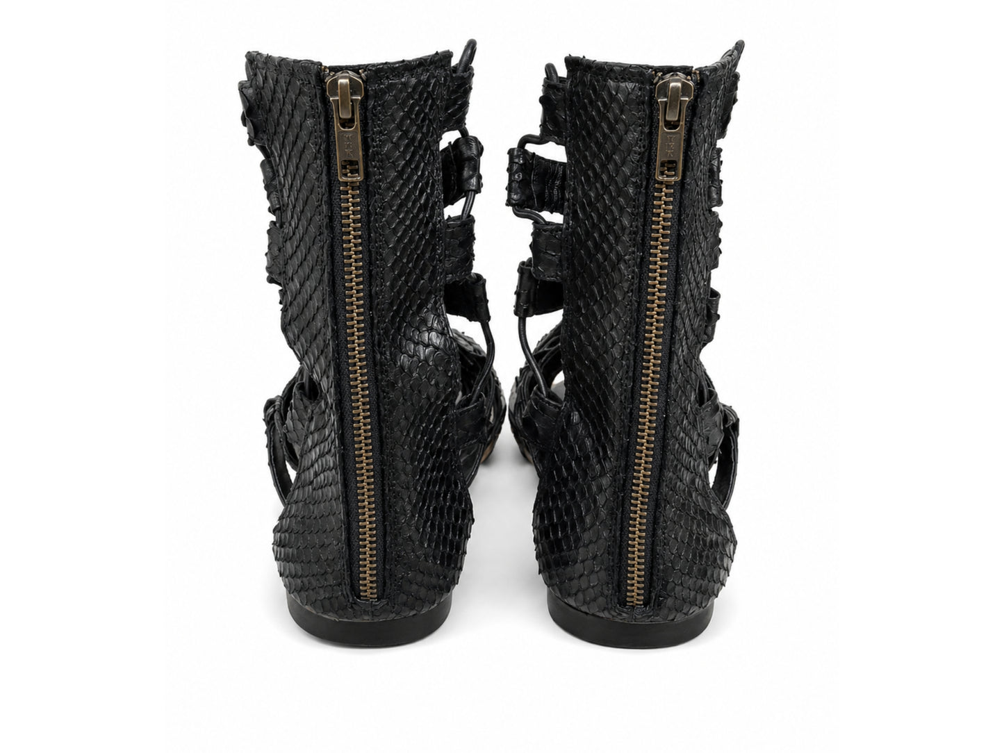 A pair of black snakeskin-textured ankle boots with side zippers and cutout straps, shown from the back against a white background.