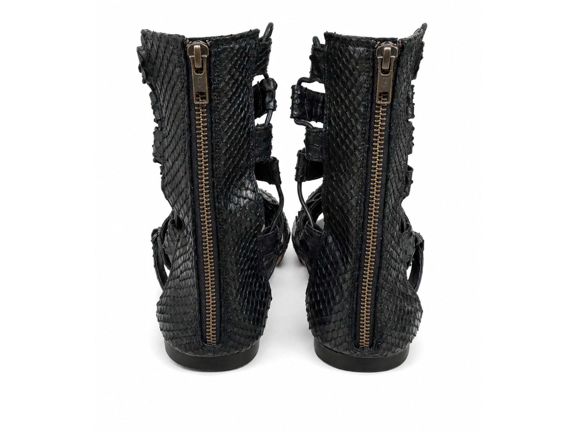 A pair of black snakeskin-textured ankle boots with side zippers and cutout straps, shown from the back against a white background.
