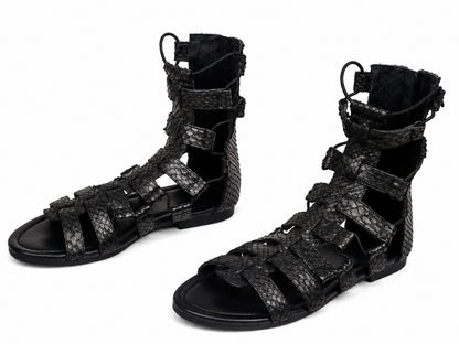 A pair of black strappy gladiator sandals with a textured python-patterned upper, shown on a plain white background.