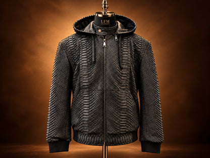 A black textured hooded jacket displayed on a mannequin against a warm brown gradient background. The jacket features a unique scale-like pattern, a full front zipper, and ribbed cuffs and hem.