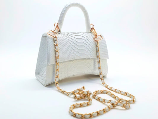 White handbag with gold chain strap on a white background
