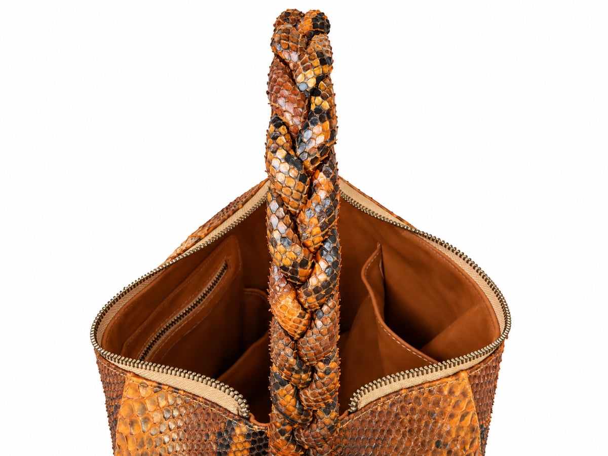 Close-up of a snakeskin-patterned handbag with a braided top handle, shown open against a plain white background.
