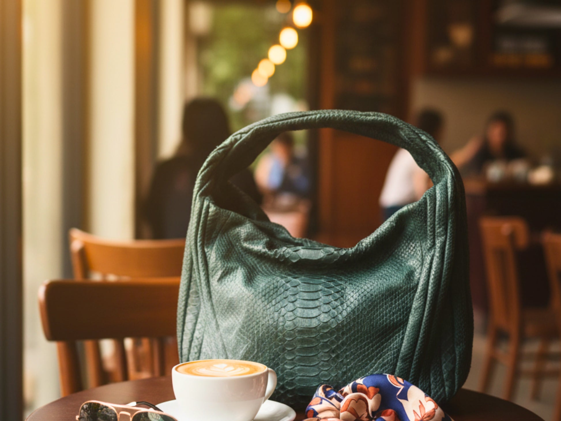Green handbag on a table with a cup of coffee in a restaurant setting
