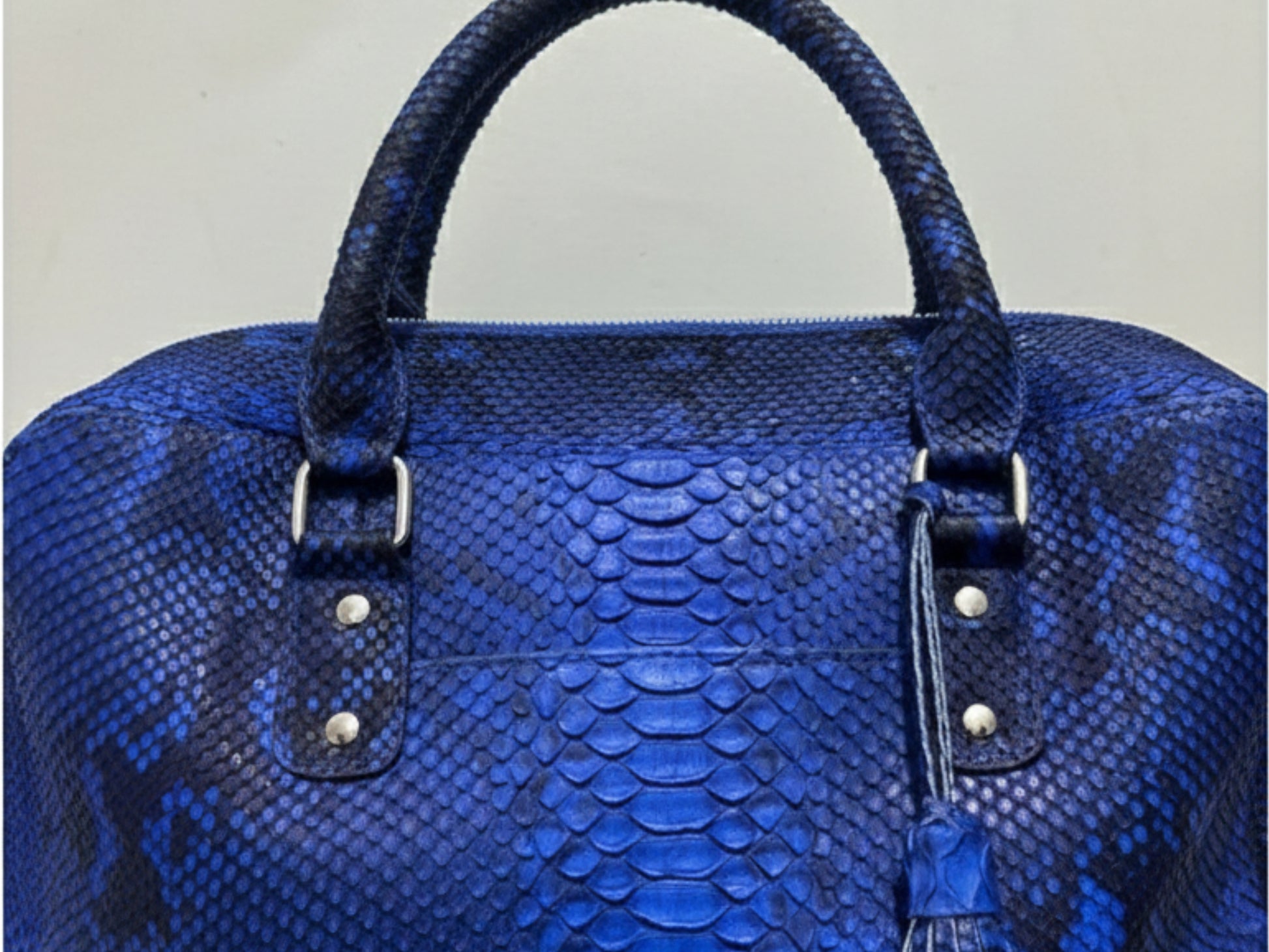 Blue textured handbag with silver hardware on a light gray background
