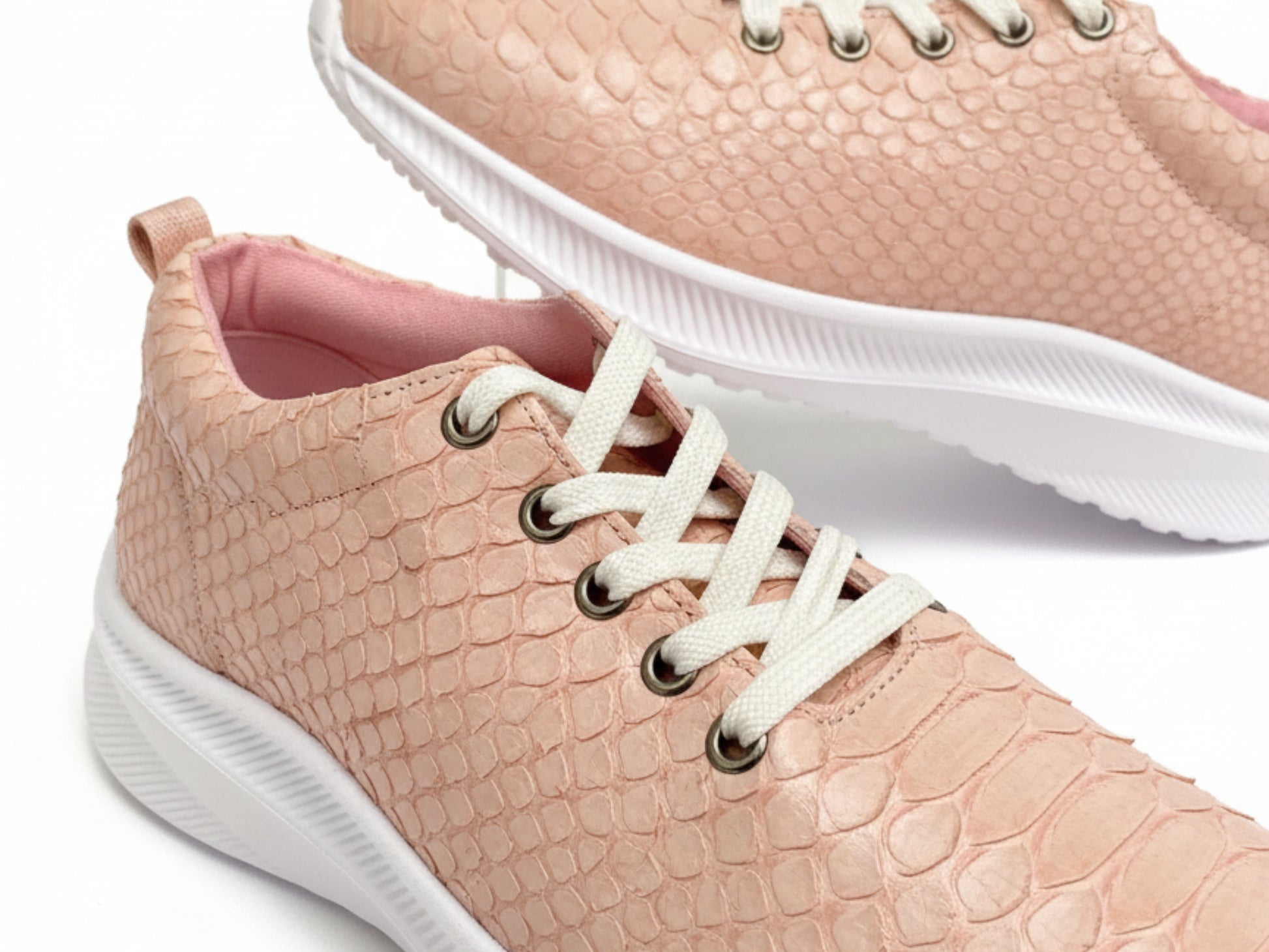 Pink textured sneakers with white laces and soles on a light background