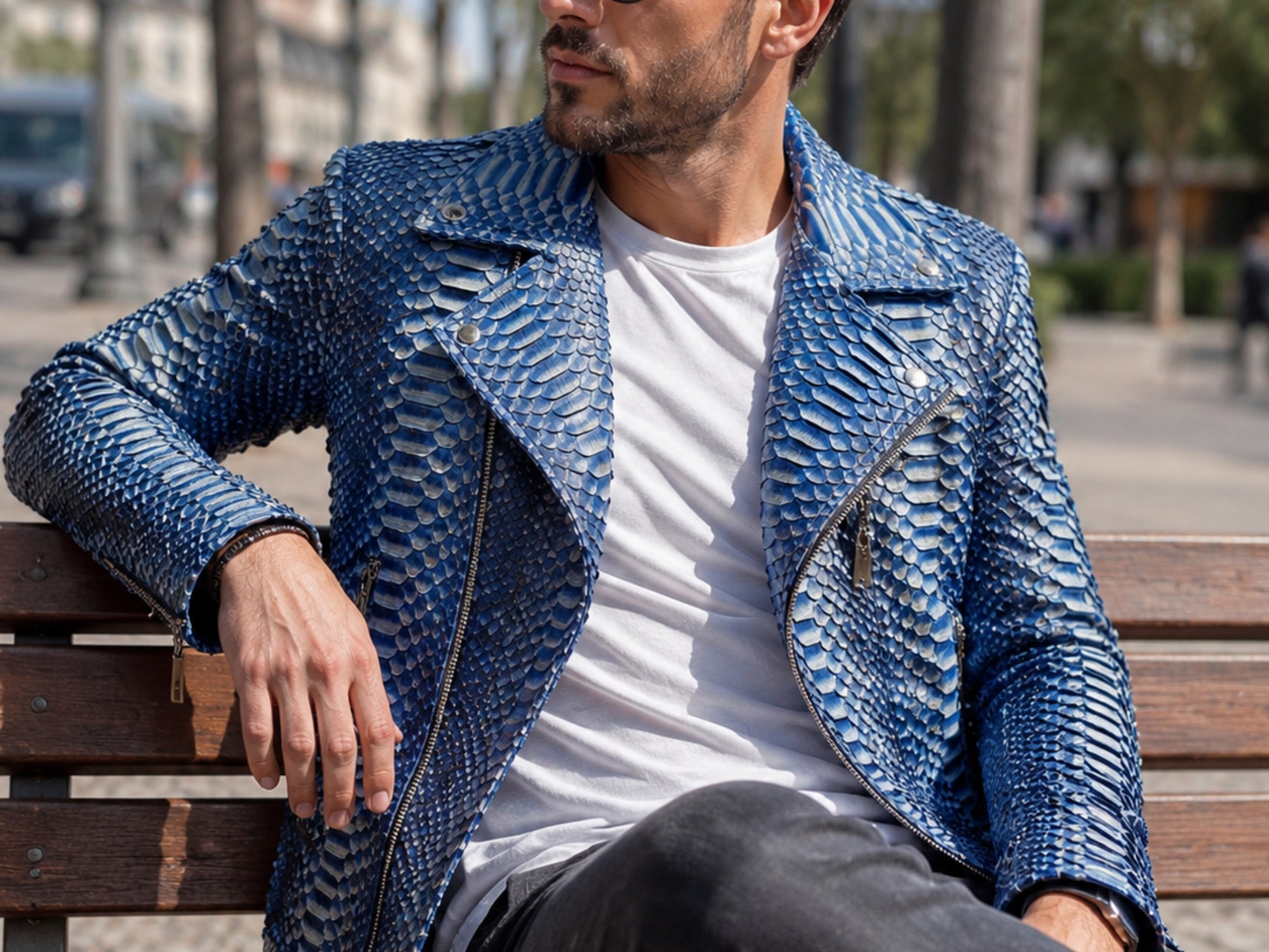 Man wearing a blue textured jacket sitting on a bench outdoors.