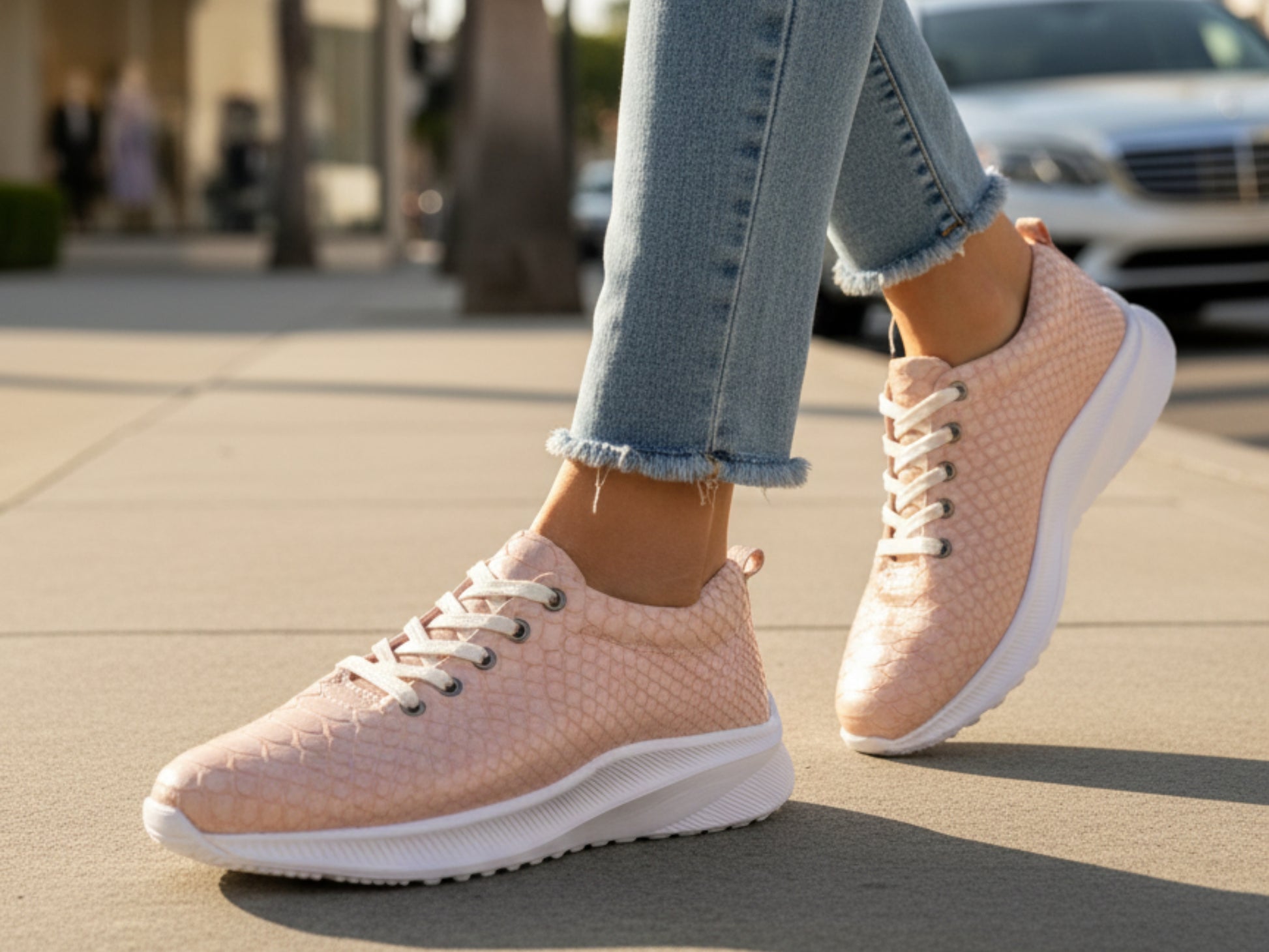 Person wearing pink sneakers with white soles on a sidewalk.