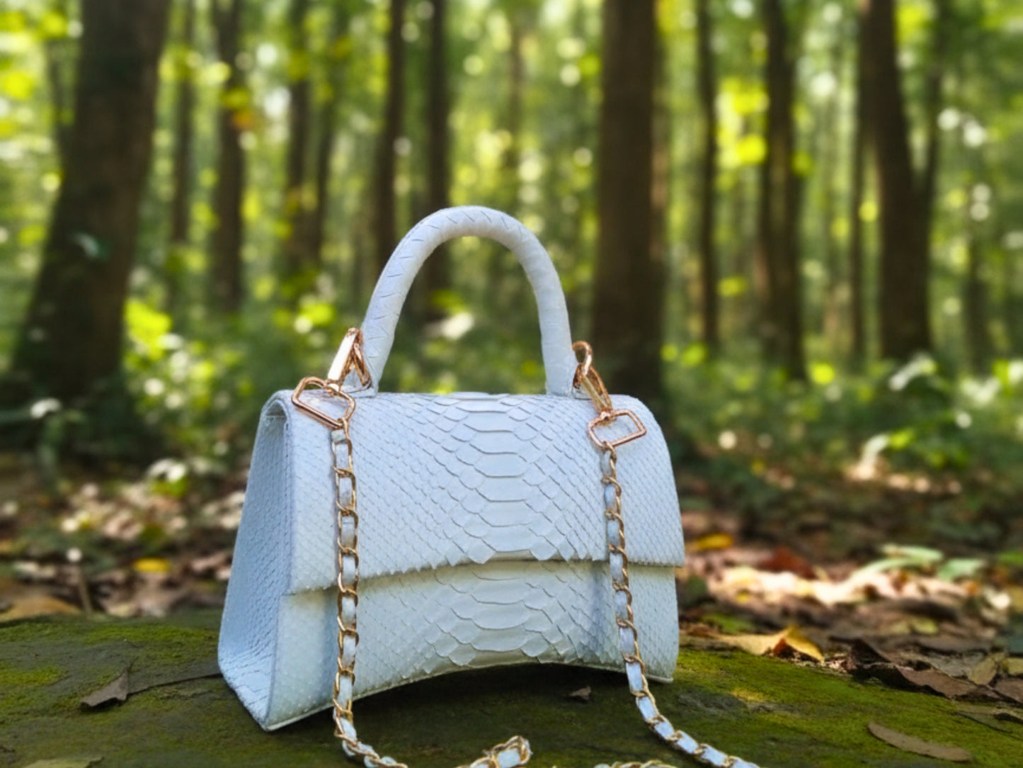 White handbag with gold chain strap on a log in a forest setting