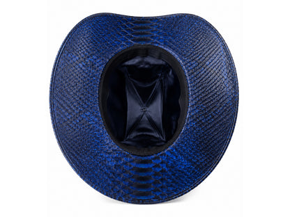 A top-down view of a wide-brimmed cowboy hat with a textured blue and black python-patterned exterior and a black satin interior, shown on a white background.