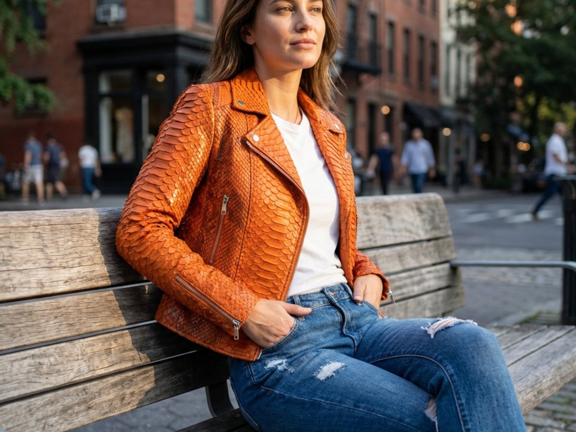 Model wearing a Genuine Python Snakeskin Leather Biker Jacket in Burnt Orange while sitting on a bench.