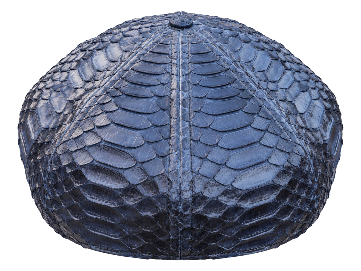 A structured cap made of navy blue python skin, showing a detailed scale texture and a central vertical seam, isolated on a white background.