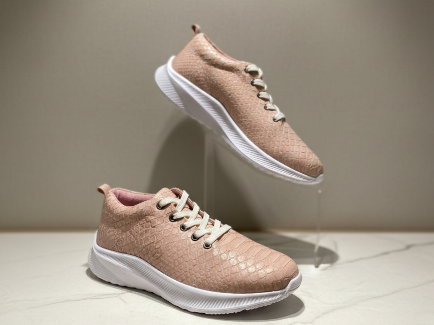 Pair of pink sneakers with white soles on a neutral background