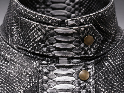 Close-up of a high-collared garment made from textured black and silver snakeskin material, featuring a structured collar with brass-tone snap buttons.