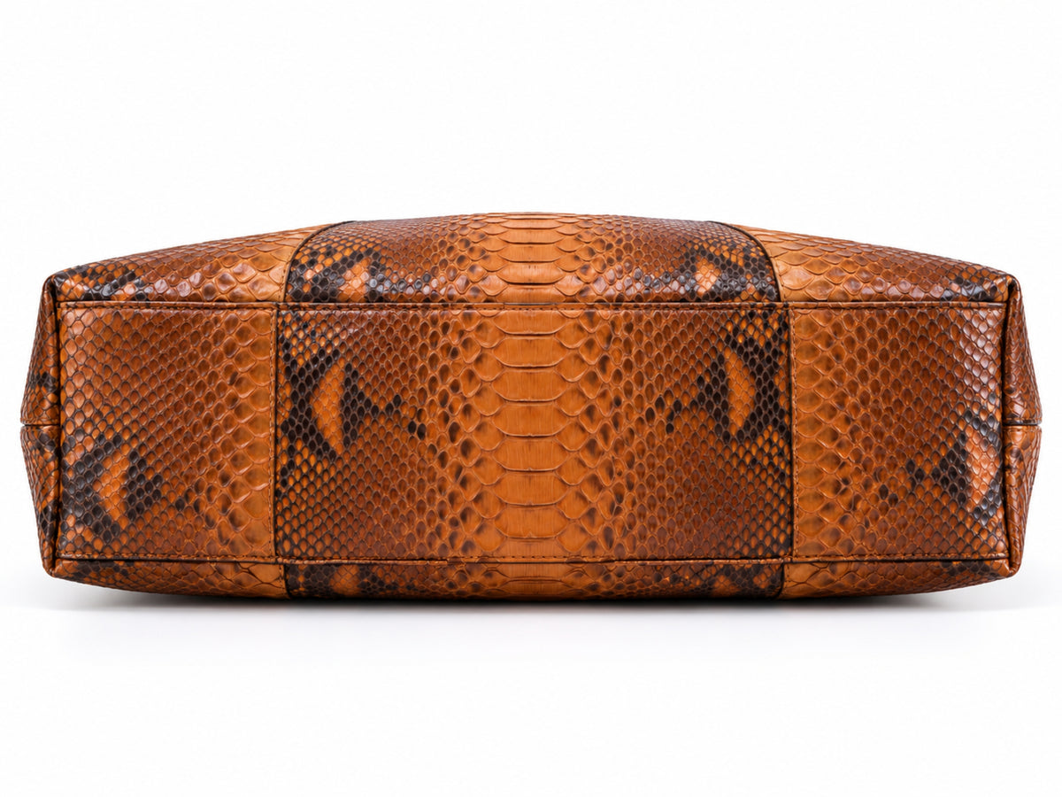 A brown and black python-patterned leather handbag shown from the back, featuring textured scales and stitched paneling, on a white background.