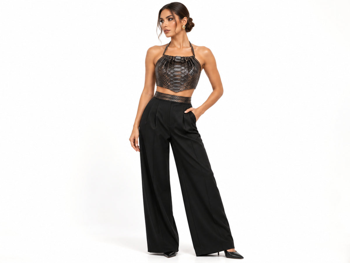A model posing in a black textured halter crop top and high-waisted black wide-leg trousers against a plain white studio background.