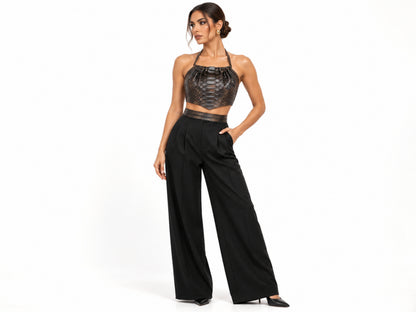 A model posing in a black textured halter crop top and high-waisted black wide-leg trousers against a plain white studio background.