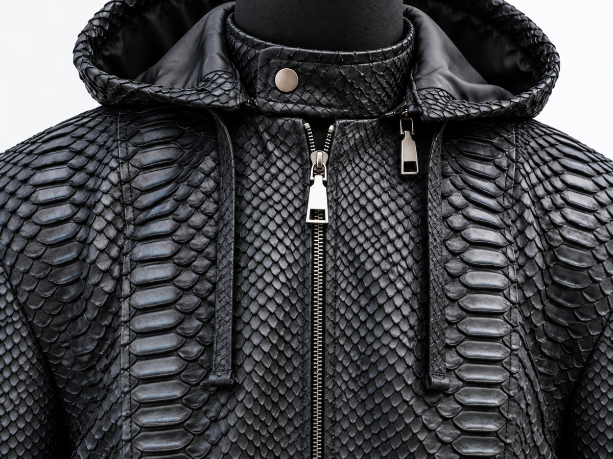 Black textured hooded jacket with a raised python-style scale pattern, front zipper, and drawstring hood, shown on a mannequin against a light gray background.