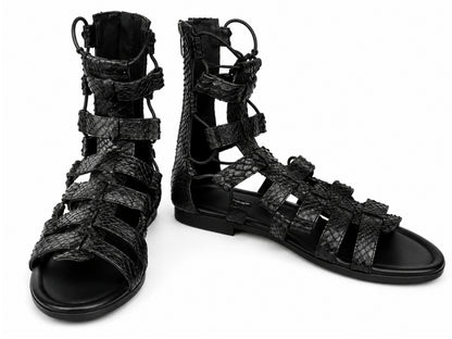 A pair of black strappy gladiator sandals with a textured python-skin pattern, shown on a plain white background.