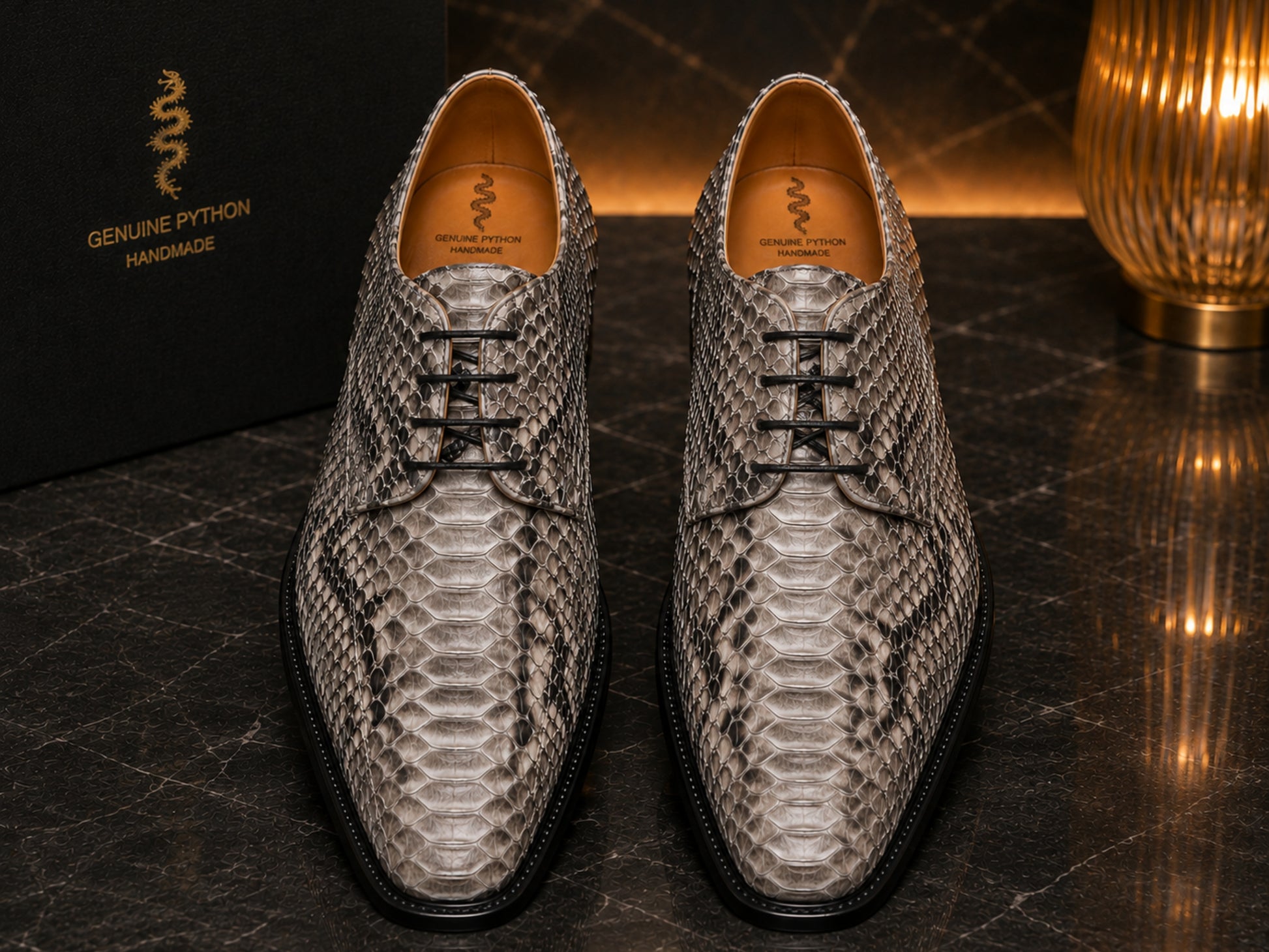 Pair of natural gray python snakeskin dress shoes displayed on black marble