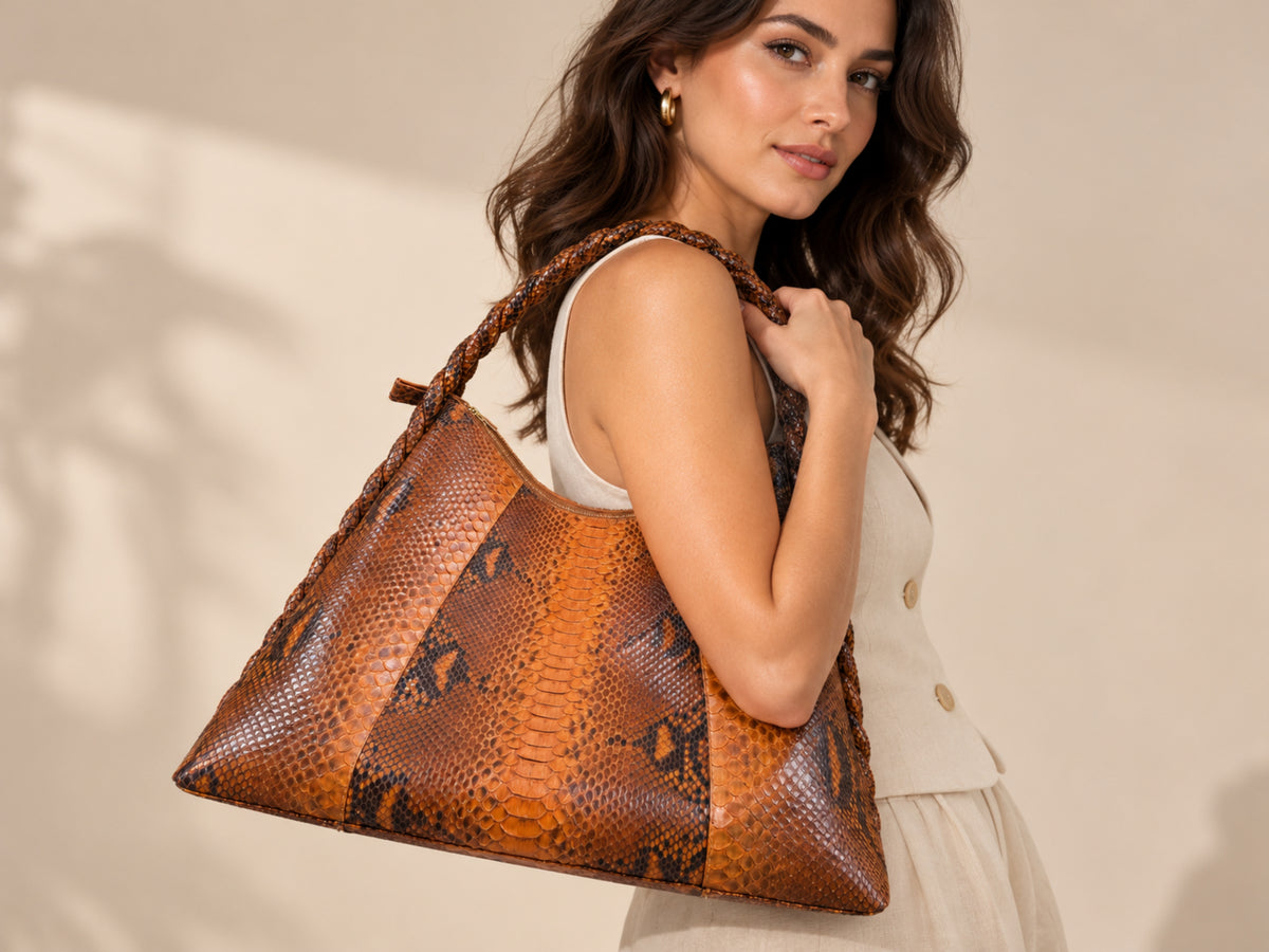 A woman wearing a white sleeveless top carries a large brown and tan snakeskin-pattern shoulder bag with braided straps against a warm beige background.