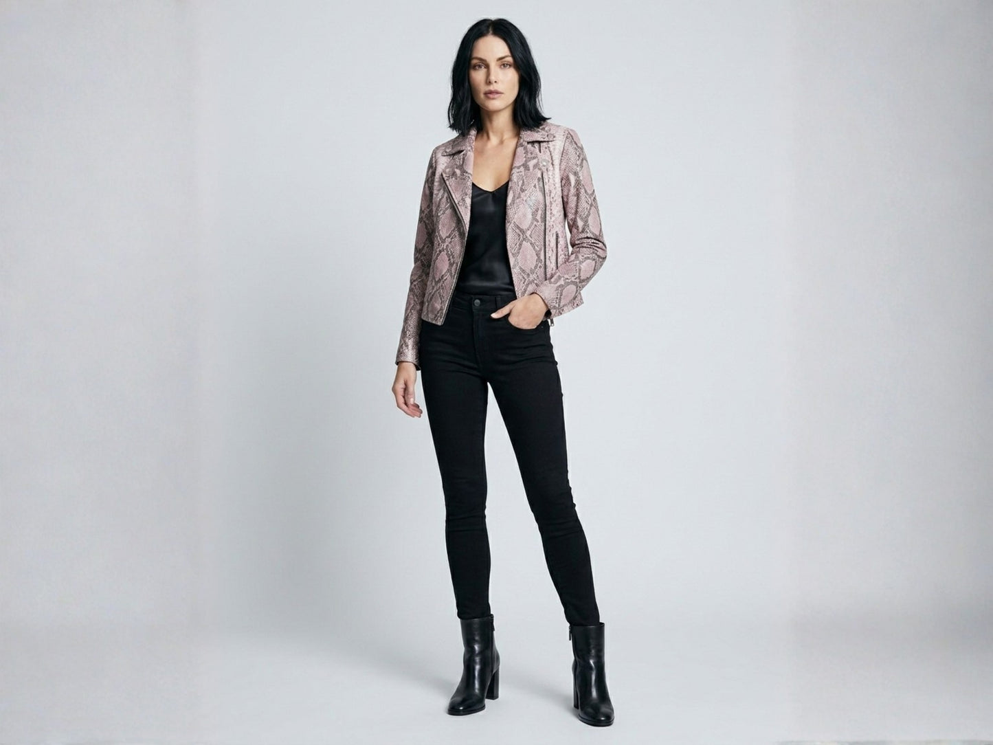 Full body studio portrait of model wearing pink python snakeskin moto jacket with black outfit