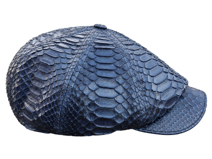A structured flat cap made of navy blue python skin, showcasing a prominent reptile scale pattern, isolated on a white background.