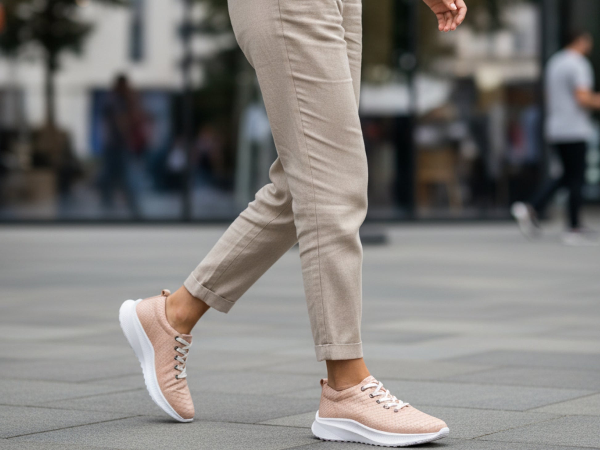 Person wearing beige sneakers and pants walking on a street.