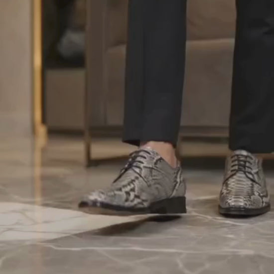 Man wearing genuine python snakeskin dress shoes with black trousers in a luxury interior