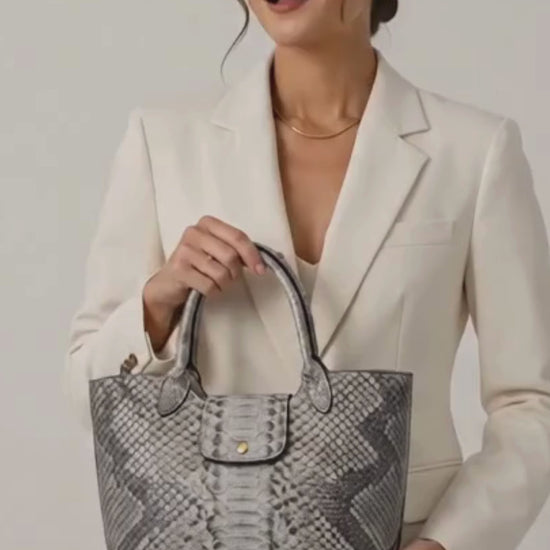 Woman wearing a cream blazer and holding a silver gray genuine python snakeskin shoulder tote bag in luxury studio