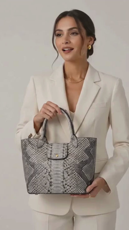 Woman wearing a cream blazer and holding a silver gray genuine python snakeskin shoulder tote bag in luxury studio