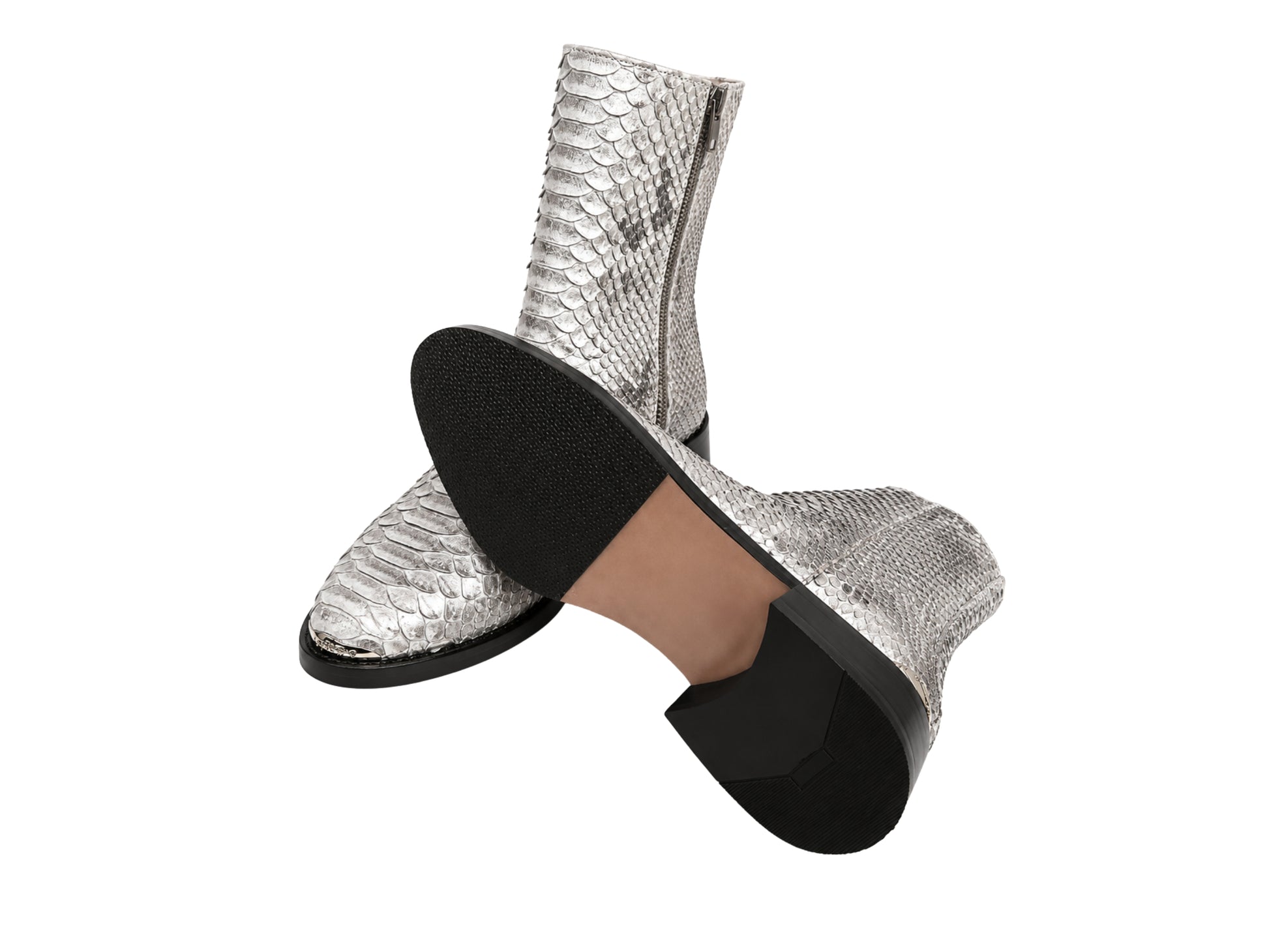 Bottom view of silver gray python snakeskin boots showing black textured soles and heels