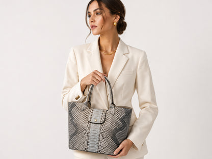Woman wearing a cream blazer and holding a silver gray genuine python snakeskin shoulder tote bag in luxury studio